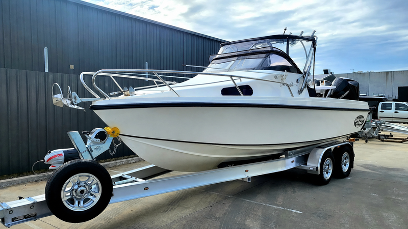 White boat on a trailer in front of a building